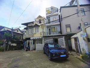 una macchina blu parcheggiata di fronte a una casa di Gold's House a Da Thanh