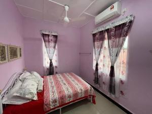 a bedroom with a bed and two windows at Dan's Homestay Bangau in Temerloh