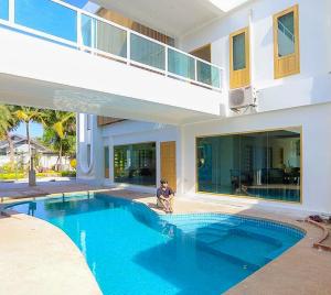 a man sitting in front of a house with a swimming pool at J Park Pakchong in Ban Sao Thong