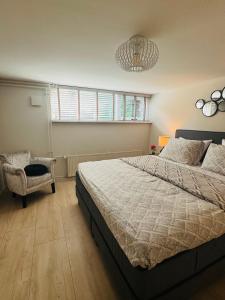 a bedroom with a large bed and a chair at Souterrain Boslaan Katwijk aan zee in Katwijk aan Zee