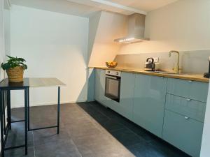 a kitchen with blue cabinets and a table at Souterrain Boslaan Katwijk aan zee in Katwijk aan Zee +7 photos