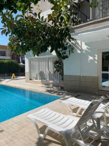 two white lounge chairs next to a swimming pool at Fora Apart Otel Cesme in Çeşme