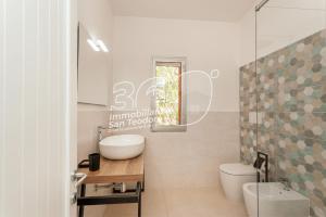 Un baño con lavabo, inodoro y espejo. en VIllino Ginepro, en San Teodoro 26 fotos más