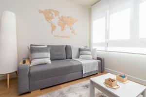 a living room with a gray couch and a world map on the wall at HOME IN CASTRO con PARKING in Castro-Urdiales
