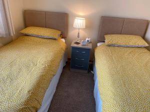 two beds in a small room with a nightstand between them at Riverside in Tarbert