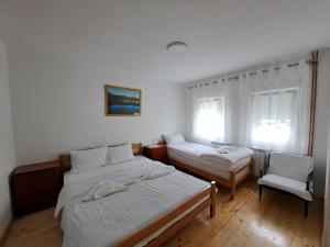 a bedroom with two beds and a chair and a window at Rooms Lida & Friendly home in Plav
