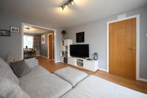 a living room with a couch and a flat screen tv at Links Golf Villa in Troon