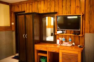 索拉哈Chitwan Riverside Resort的配有电视和木墙的房间