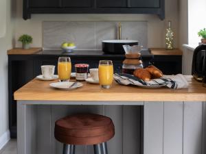a kitchen with a breakfast table with orange juice and croissants at Sweetslade Cottage in Bourton on the Water +16 photos