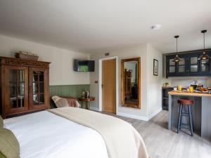 a bedroom with a white bed and a kitchen at Sweetslade Cottage in Bourton on the Water
