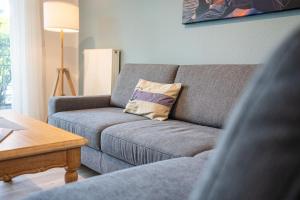 a living room with a gray couch with a pillow at Stern FeWo Strandstraße in Ostseebad Karlshagen