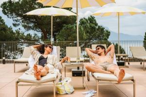 a man and woman sitting in lawn chairs under umbrellas at Hotel Mona Ex-Eurotel in Montreux