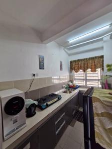 a kitchen with a counter top with a stove and a bed at Anggerik Camelia Homestay Apartment Ladang Tok Pelam FREE WIFI in Kuala Terengganu