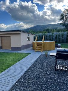 un patio trasero con una casa y un parque infantil en Chalupa na Bílé Vodě, en Červená Voda