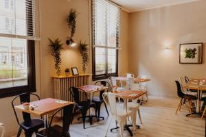 a dining room with tables and chairs and windows at L'Hôtel Bristol in Caen