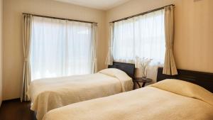 two beds in a room with a window at Rereso沖縄美ら海 in Motobu