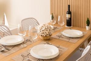 a wooden table with white plates and wine glasses at HOME IN CASTRO con PARKING in Castro-Urdiales