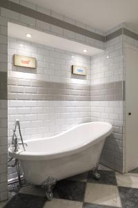 a white bath tub in a bathroom with gray tiles at Palm House - Luxury Wye Valley Country House 2 Bed Apartment - Dog Friendly in Newland