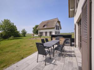 a patio with a table and chairs and a house at Reetland am Meer - LuxusPlus Reetdachvilla mit 4 Schlafzimmern, Außensauna, Loungebereich und Kamin H06 in Dranske