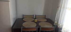 a dining room table with four chairs and a black table at Apartament Miruna in Moineşti +2 photos