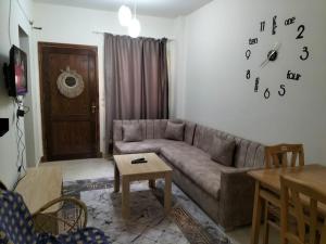a living room with a couch and a clock on the wall at Makkadi Orascom Chalet in Sahl Hasheesh