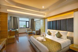 a bedroom with a large bed and a living room at Hotel Saffron Leaf in Dehradun