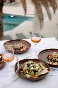 una tavola con piatti di cibo e bicchieri di vino di Pnoi Hotel a Logaras
