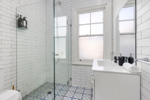een witte badkamer met douche en wastafel bij Vacation Home w Private Rooftop and Harbour View in Sydney