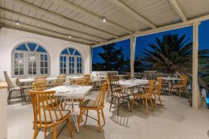a dining room with tables and chairs on a patio at Pnoi Hotel in Logaras