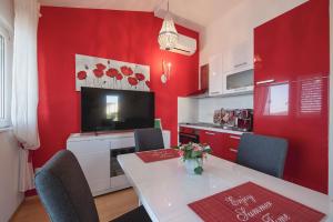 Una cocina con paredes rojas y una mesa con sillas. en Studio Apartments Mack - GOLD, en Sevid