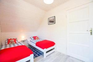 two beds in a small room with a door at Domki Całoroczne Klif Ustka - Nowoczesne Dwupoziomowe Domki Nad Morzem in Ustka