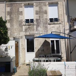 a blue umbrella and chairs in front of a building at Les galets in Fouras +1 photo