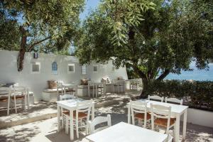 a restaurant with white tables and chairs under trees at Akti Hotel Kavala in Paleo Tsifliki