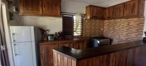 a kitchen with wooden cabinets and a white refrigerator at Maison Angèle in Nosy Be +7 photos