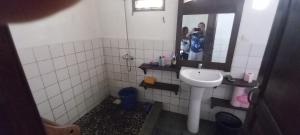 a bathroom with a sink and a person in a mirror at Maison Angèle in Nosy Be