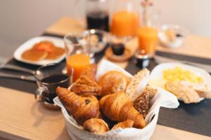 a table topped with a basket of pastries and orange juice at Corte Novella Hotel & Residence in Brescia