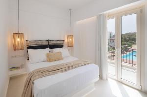 a white bedroom with a bed and a large window at Country Villas in Stelida