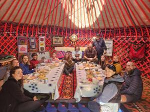 a group of people sitting around a table in a yurt at Sayakat Eco Camp in Kaji-Say