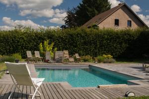 una piscina con una silla y una casa en B&B La Raveline en Sart-lez-Spa