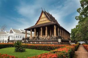 a pagoda in a garden in front of a building at Senesouk Hotel in Vientiane