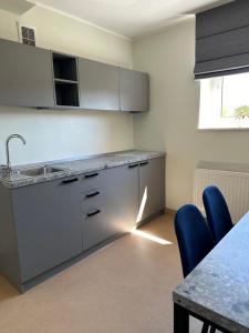 a kitchen with a sink and a table with blue chairs at VESK Veisiejai in Veisiejai