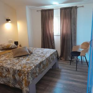 a bedroom with a bed and a chair and a window at MARANGUN Drage apartman in Drage