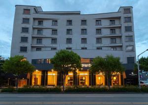 IksanTop Cloud Hotel Iksan的一座白色的大楼，前面有树