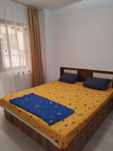 a bedroom with a bed with a blue and yellow comforter at Apartament Daniela in Năvodari