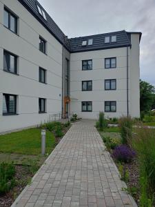 a white building with a brick walkway in front of it at Apartament Bieszczadzka A 8 Lesko in Lesko +6 photos
