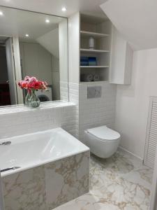 a bathroom with a tub and a toilet and a vase of flowers at Appartement privé avec jardin in Boulogne-Billancourt
