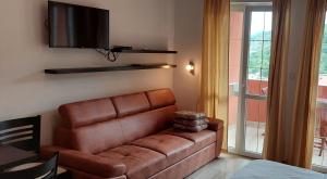 a brown leather couch in a living room with a television at Apartments Danilo Kažanegra in Sveti Stefan