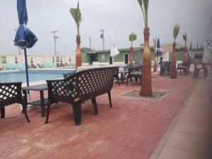 a row of benches next to a pool with palm trees at Complex Amazon Guercif in Guercif