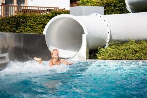 un jeune enfant est dans un bassin profond dans une piscine dans l'établissement Schöneben Chalet Enzian, à Wald im Pinzgau
