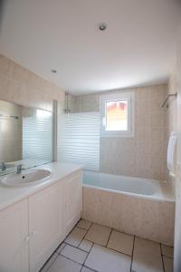 a bathroom with a tub and a sink and a mirror at Appartement 29 Plages à pied in Capbreton